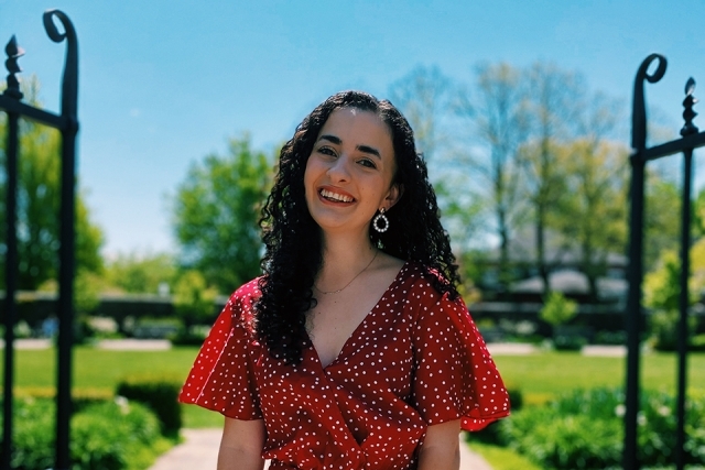 Emma Famili posing for a picture outside with a fence and grass behind her