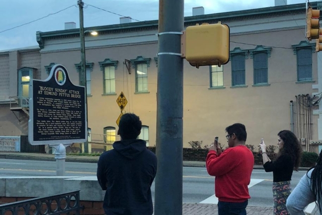 St. John’s Students Immerse Themselves in Civil Rights History. Group of students taking photo of historic sign on street corner. 