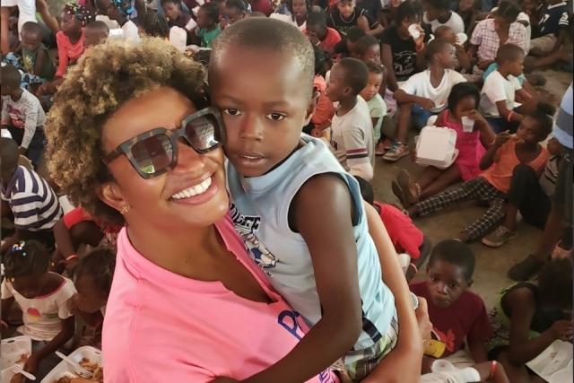 Female holding a young child while smiling at the camera
