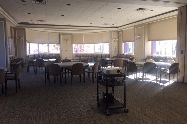 An empty banquet room with chairs and a projector