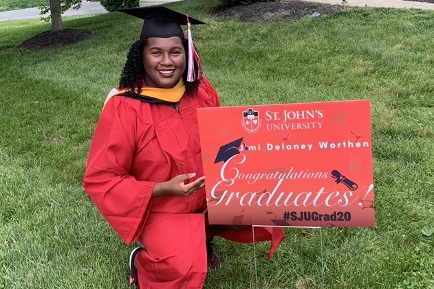 J’mi Worthen posing with Commencement yard sign