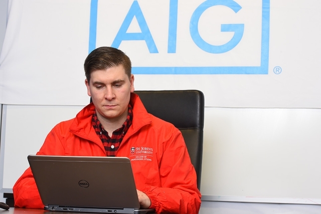 Kevin Kaulfers on his laptop with AIG logo behind him on the wall