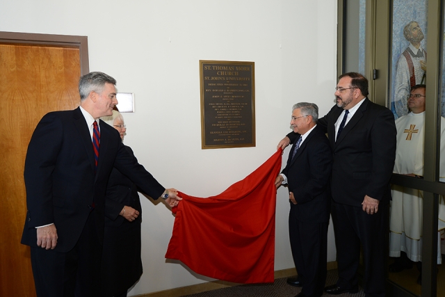 People unveiling wall plaque at St. Thomas More Church