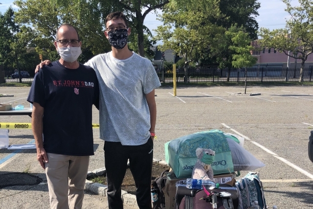 Father and Son posing for photo in parking lot with bags