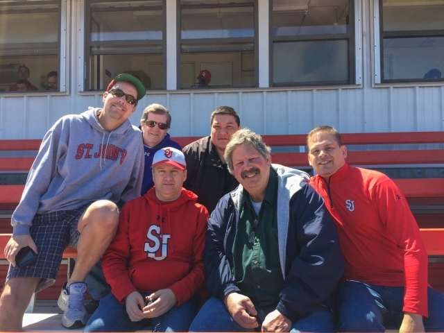 Alumni Wendell Cruz, Darrin Kneute, Mike Maher and Brian Tighe in bleachers attending a baseball game  