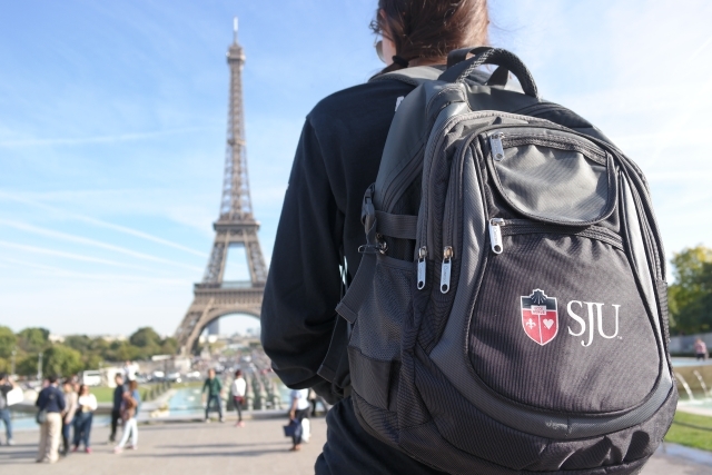 Student with SJU backpack looking at the Eiffel Tower