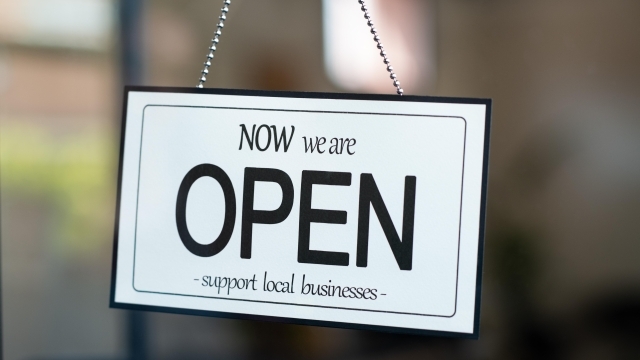 A sign that reads, "Now we are OPEN support local business" in the window of a door