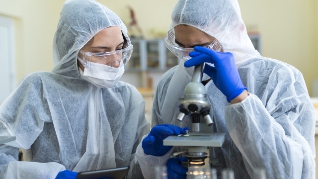 Two students in PPE at a microscope
