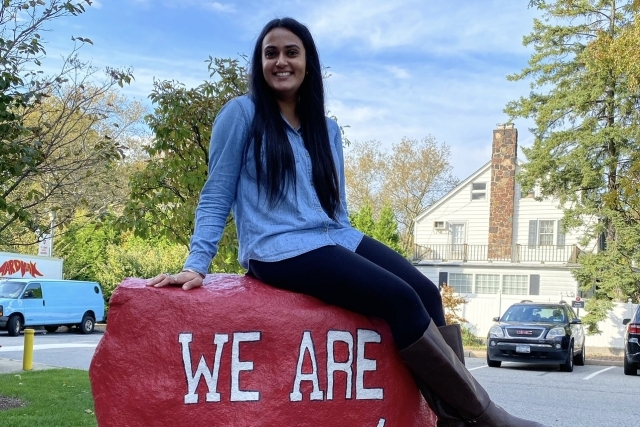  Avneet Nagra '17TCB, '18MS sitting on red rock with We Are St Johns painted on it