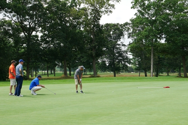 St. John's alumni and friends playing golf outside on the course