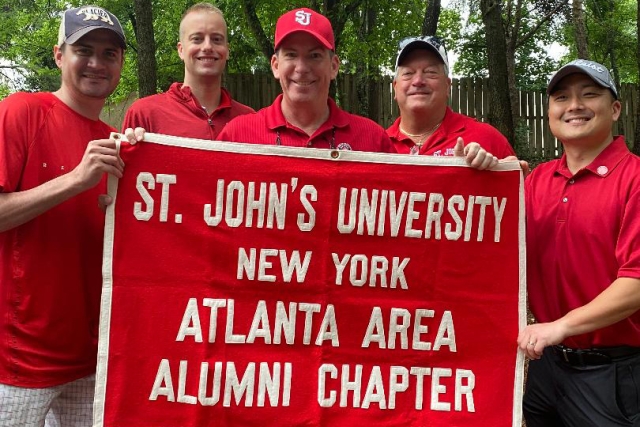 St. John's University Atlanta Area Alumni Chapter banner held by five St. John's alums
