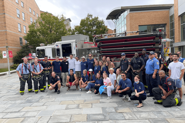 Students and firefighters pose for a picture outside on campus