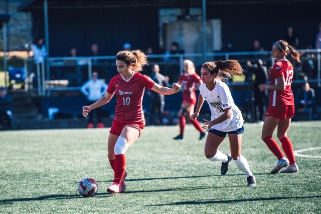 St. John's womens soccer player keeping ball away from Georgetown soccer player