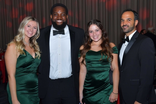 4 individuals standing on stage posing for photo