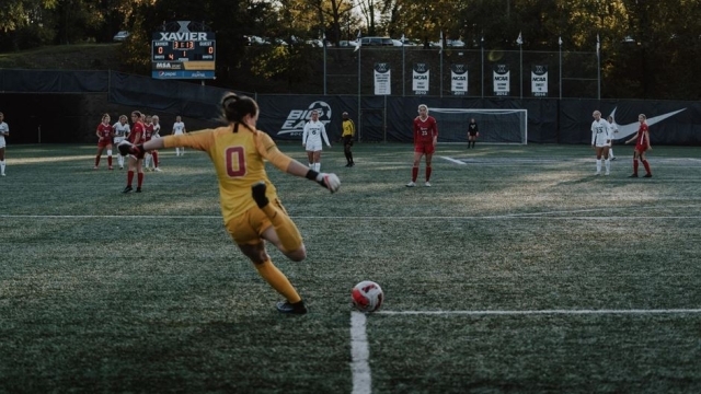 Female soccer goalie kicking the ball from the corner of the box to teammates on the field
