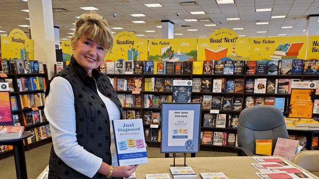 Arlene M. Karole posing with her book in a bookstore