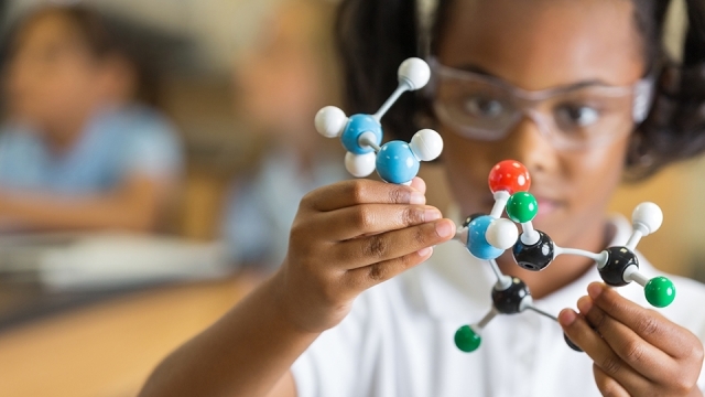 Female elementary student looking at molecule model