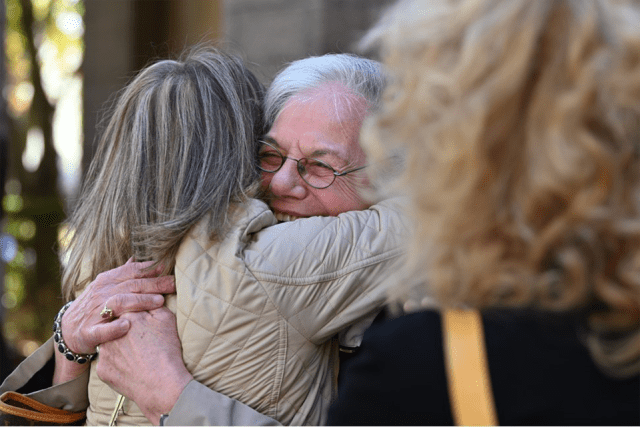 Two St. John's retirees embrace for a hug