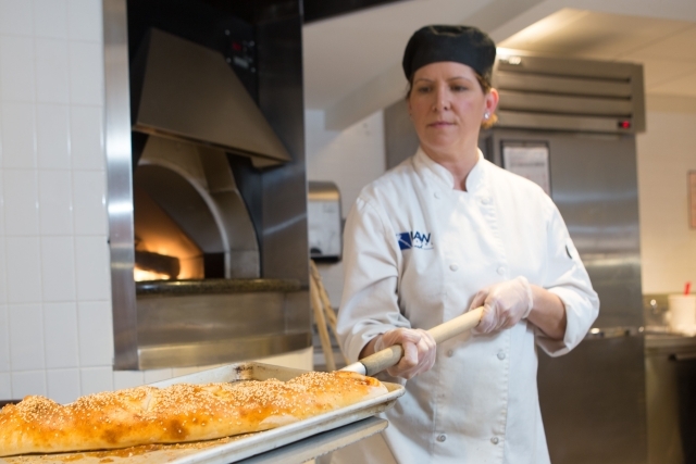 A female chef taking bread out of the oven