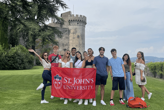 Johnnies in Rome pose for a photo with St. John's banner