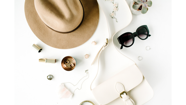 Hat, sunglasses, purse and other accessories scattered against a white background