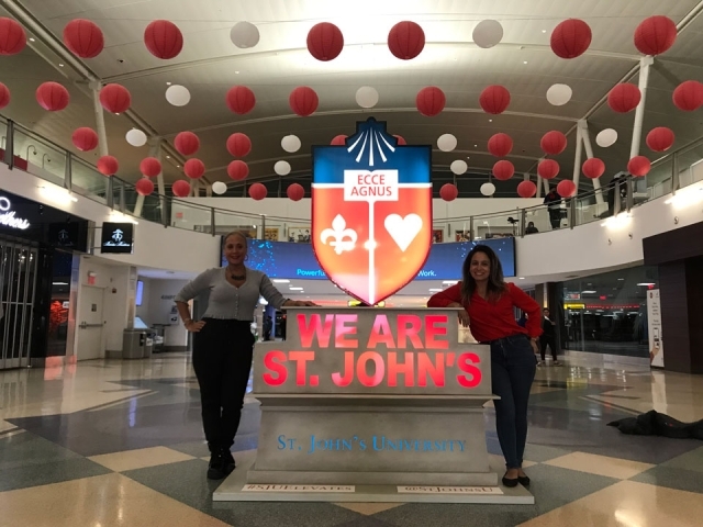 Odaris Ithier-Olle and Elena Damiani next to St. John's crest statue in JFK Airport