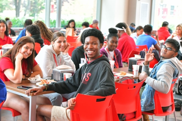 Students smiling while sitting at a table for orientation