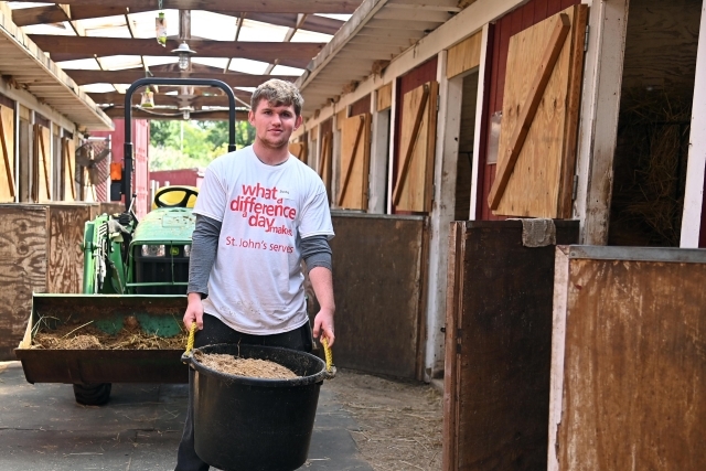 Male student cleaning up barn as a service activity