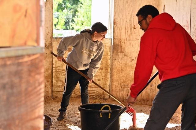 Two students cleaning up barn during while conducting service 