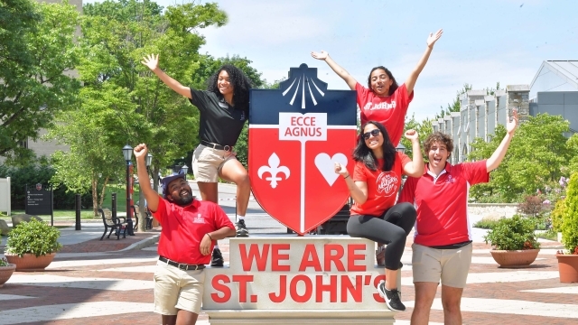 Students posing on and around the We Are St. John's Statue 