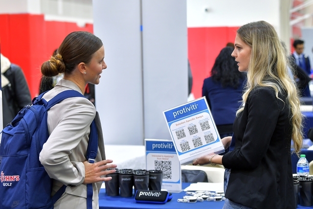 Two females speaking to one another at career fair