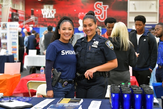 Two police woman posing for photo together at career fair