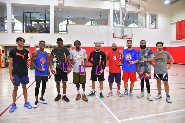Group of 9 men posing for photo on basketball court after charity game 