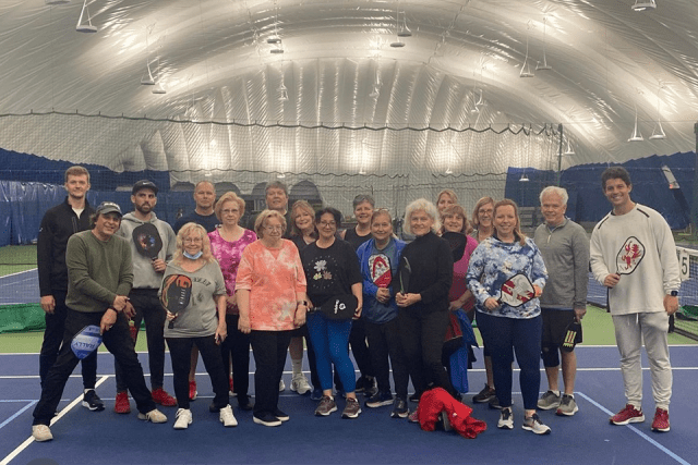 Alumni gather for a group picture on the pickleball court