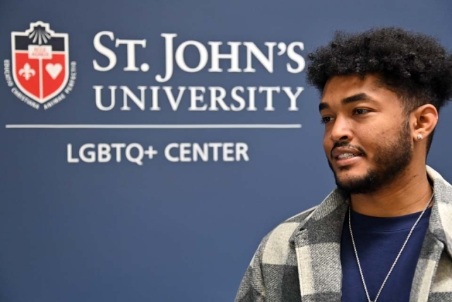 Student at LGBTQ Center Open House in front of banner