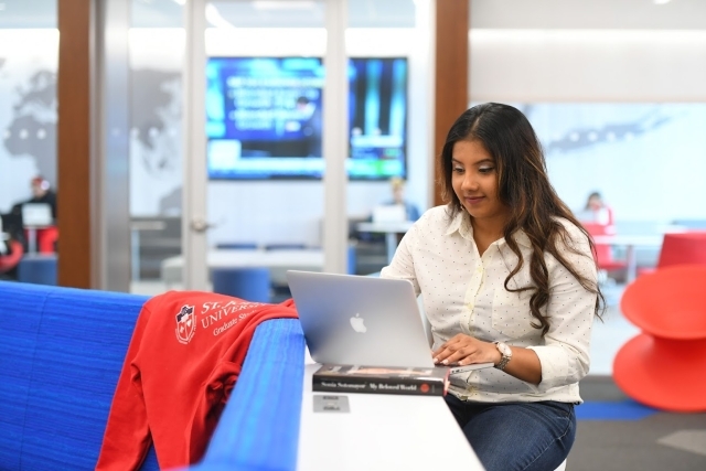 Female student sitting at table working on computer 