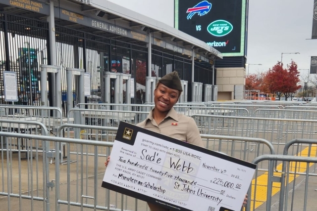 Sadé Webb holding a scholarship check infront of MetLife stadium