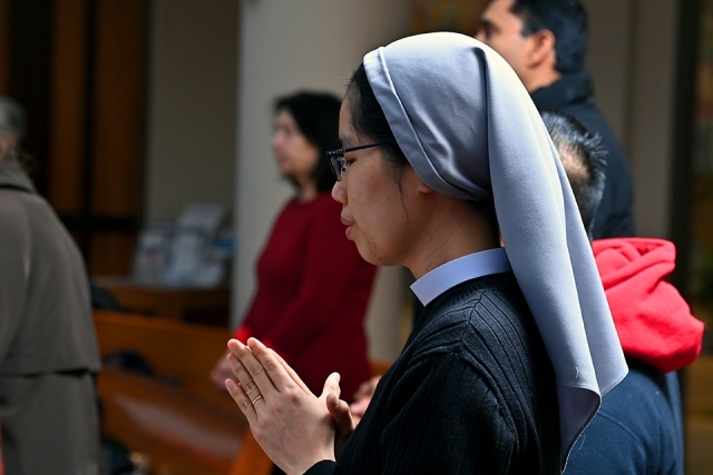 A nun prays in the pew