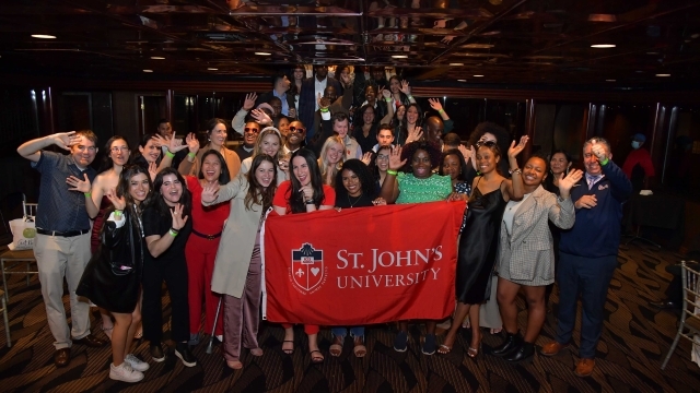 St. John's Alumni group holding banner posing for photo