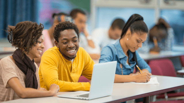 Male student sitting with female student smiling with labtop 