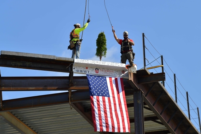 Three union workers putting beam in place with American flag hanging from it