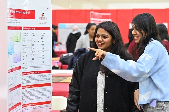 Two women talking in front of a poster at the Student Research Conference