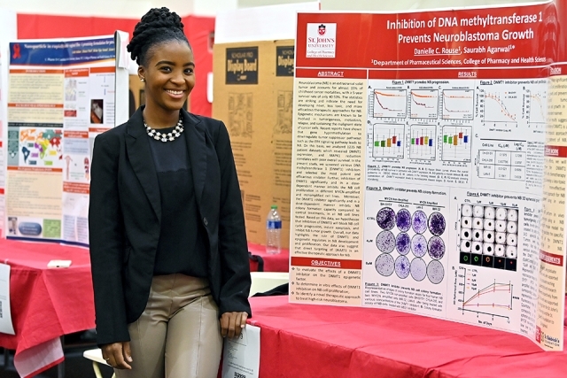 A student and their trifold poster at the Student Research Conference 