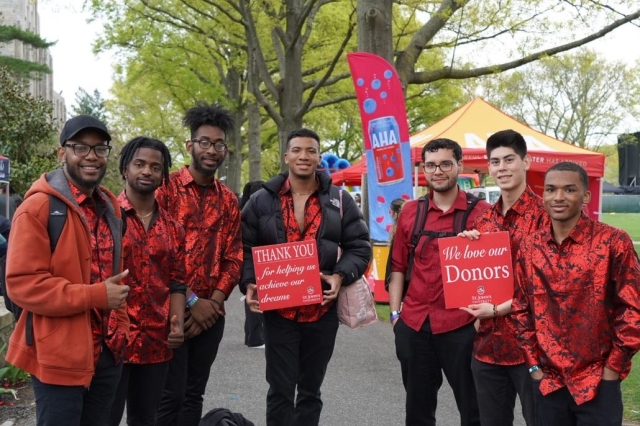 A group of St. John's Students holding a Thank A Donor Sign on great lawn