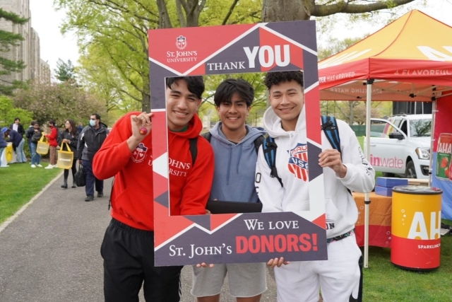 St. John's Students holding a Thank A Donor Sign on great lawn