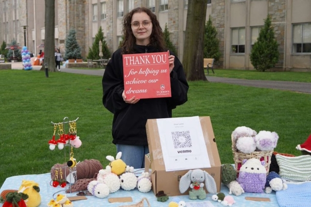 St. John's Student holding a Thank A Donor Sign on great lawn