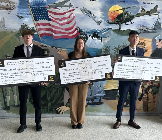 Three students holding up checks to celebrate St. John's Minuteman Scholarship
