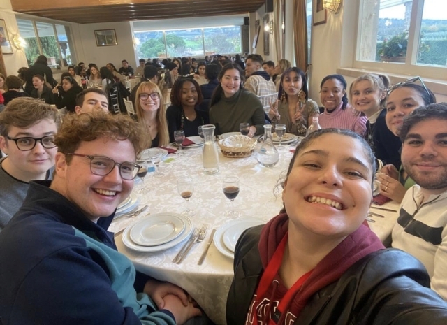 Group of male and female study abroad students smiling at a table 