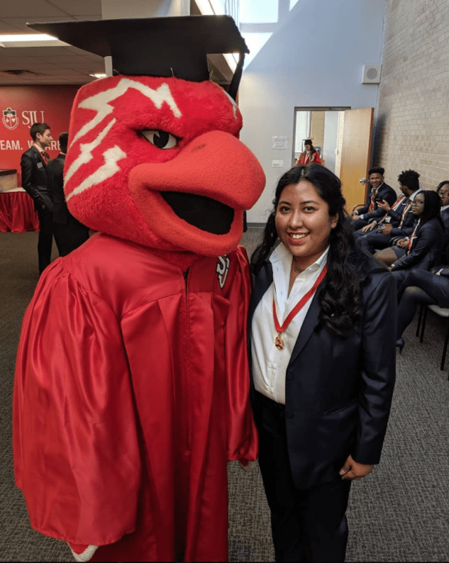 St. John's alumna standing next to red johnnies bird mascot