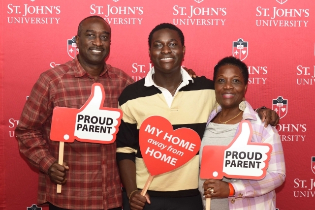 St. John's student with parents posing for photo with photo booth props
